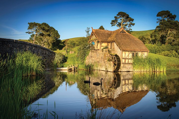 Discover the charm of Hobbiton with its idyllic landscape featuring charming cottages reflected in serene waters perfect for those seeking a picturesque escape in New Zealand's countryside.